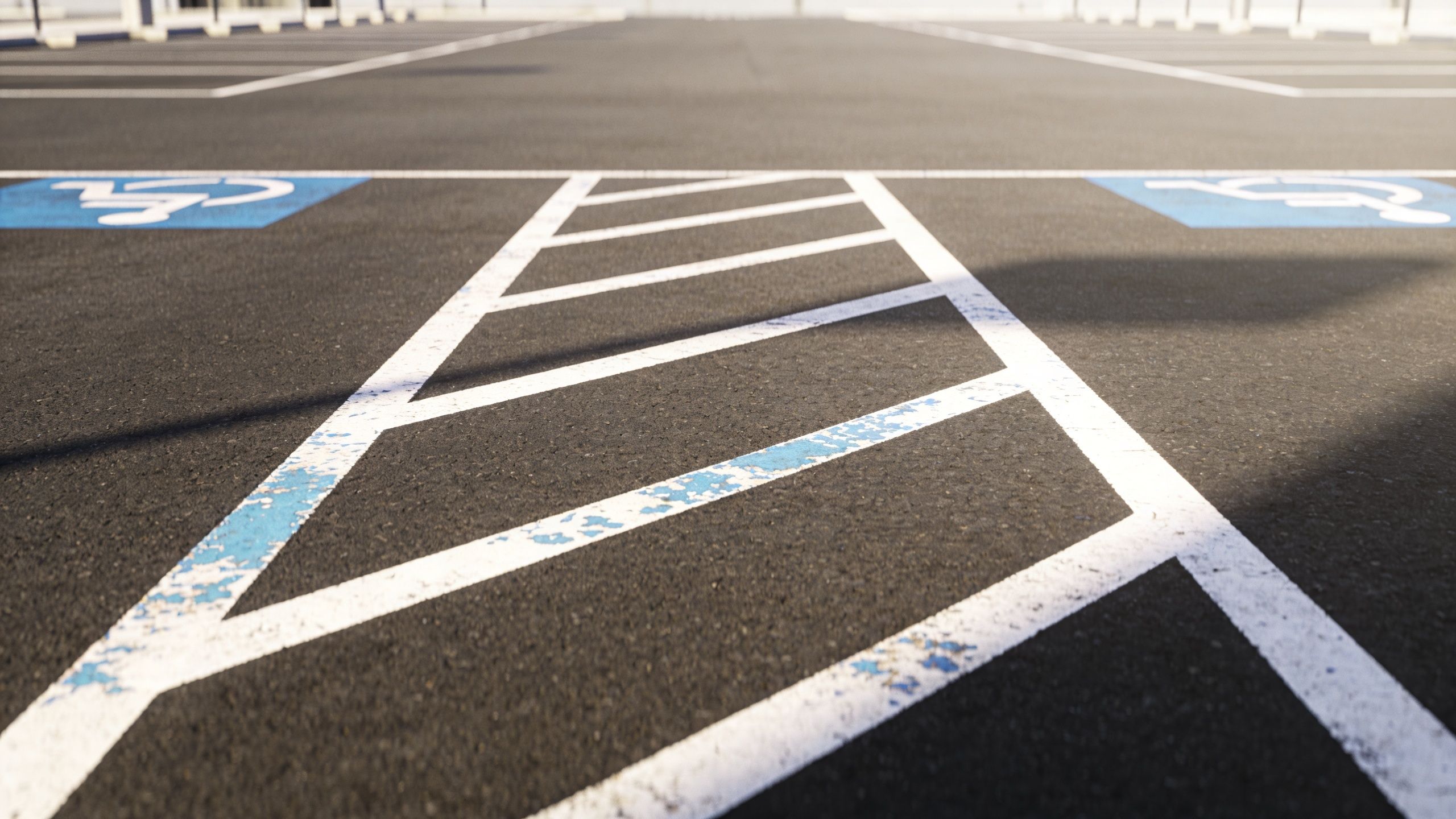 A close up view of an accessible parking space with blue and white pavement striping and symbols.