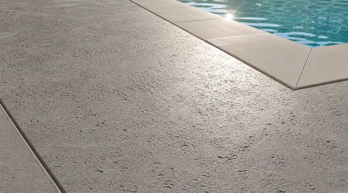 A close up view of a modern swimming pool deck featuring textured concrete finishing techniques.