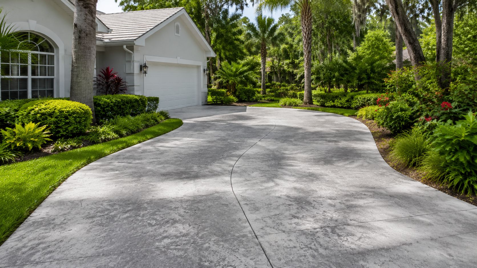A scenic view of a modern house exterior with a clean, well-maintained stamped concrete driveway and landscaping.